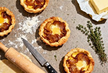 Tartelette oignon caramélisé avec pâte feuilletée dorée et garniture onctueuse sur plan de travail encombré