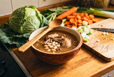 Garbure du sud-ouest servie dans un bol traditionnel avec confit de canard, haricots blancs et légumes frais sur un plan de travail