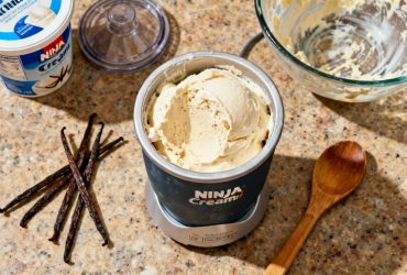 Glace vanille maison dans un contenant ninja creami posé sur un plan de travail de cuisine avec gousses de vanille et ustensiles