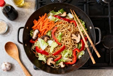 Nouilles chinoises aux légumes colorés dans un wok, avec carottes, poivrons rouges, chou et champignons shiitake