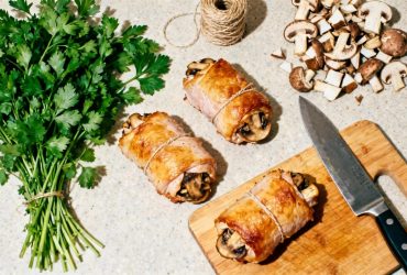 Paupiettes de dinde dorées farcies aux champignons sur un plan de travail de cuisine avec persil et couteau de chef